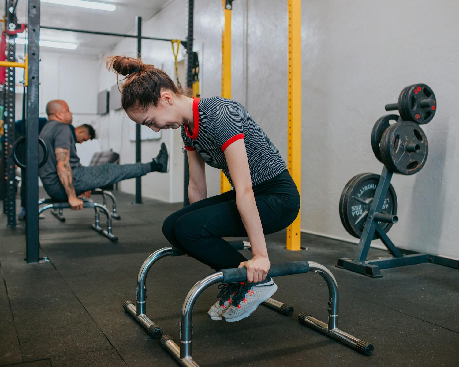 Focused group of young adults exercising intensely with gym equipment indoors.