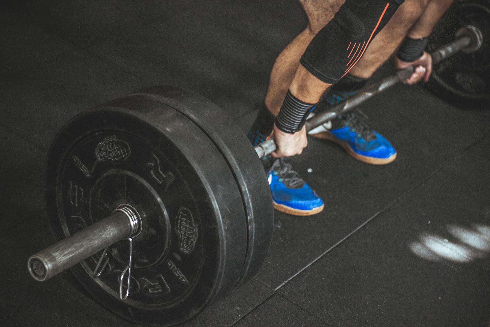 A man performing a deadlift with a heavy barbell in a gym setting, showcasing strength and fitness.